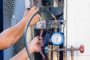 Tech checking AC refrigerant with gauge