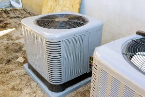 Two outdoor condensers on pads at a job site