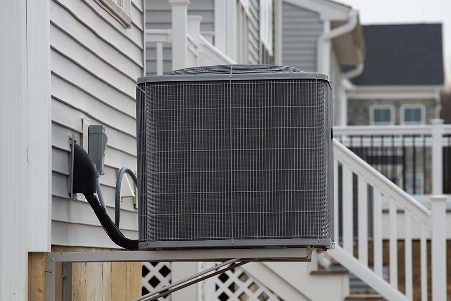 Outdoor condenser mounted on a raised platform beside a home