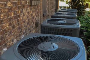 Row of outdoor condensers along a brick wall
