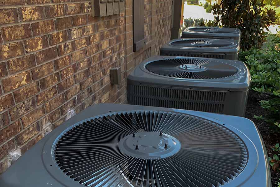 Row of outdoor condensers along a brick wall