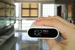 Hand holding a portable PM2.5 air quality monitor indoors