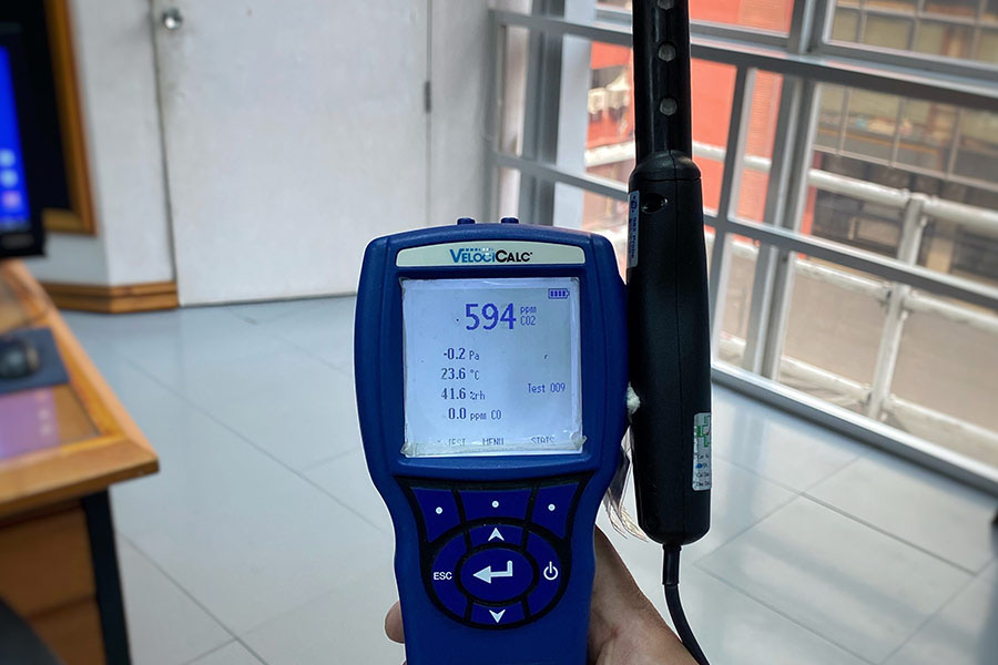 Technician holding a meter showing a 594 ppm carbon dioxide reading