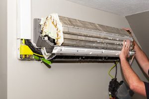 Technician cleaning the coil of a wall mounted mini split indoor unit